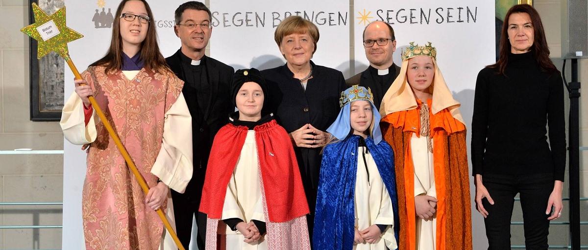 Das Bild zeigt Sternsinger bei Angela Merkel