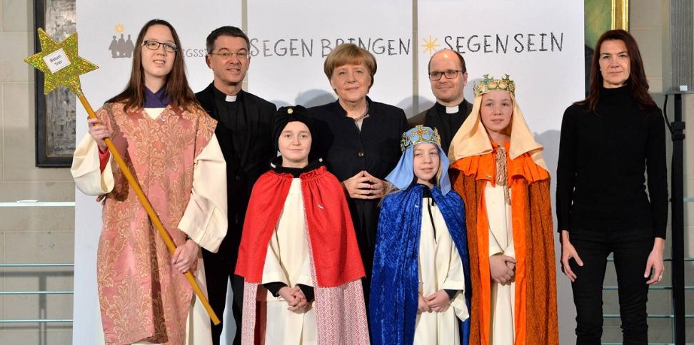 Das Bild zeigt Sternsinger bei Angela Merkel