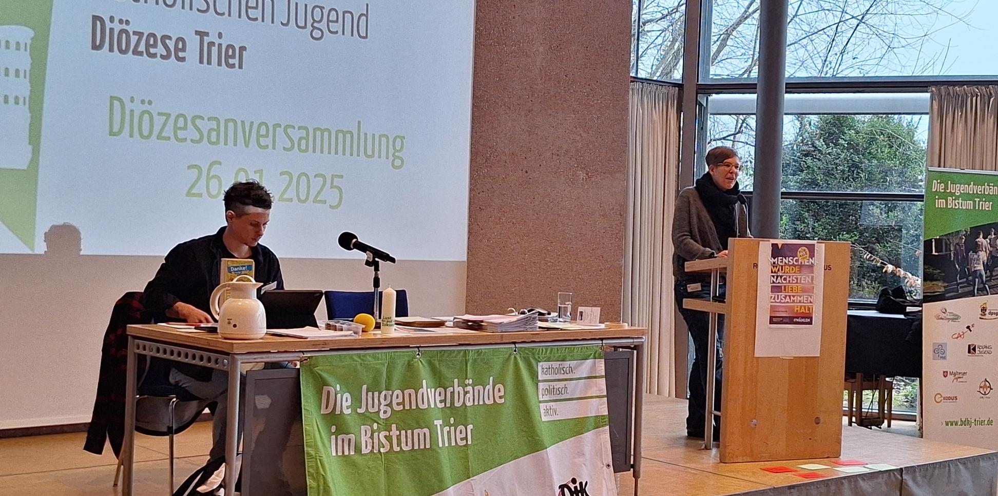 Das Bild zeigt ein Podest mit Rednerpult und Leinwand.