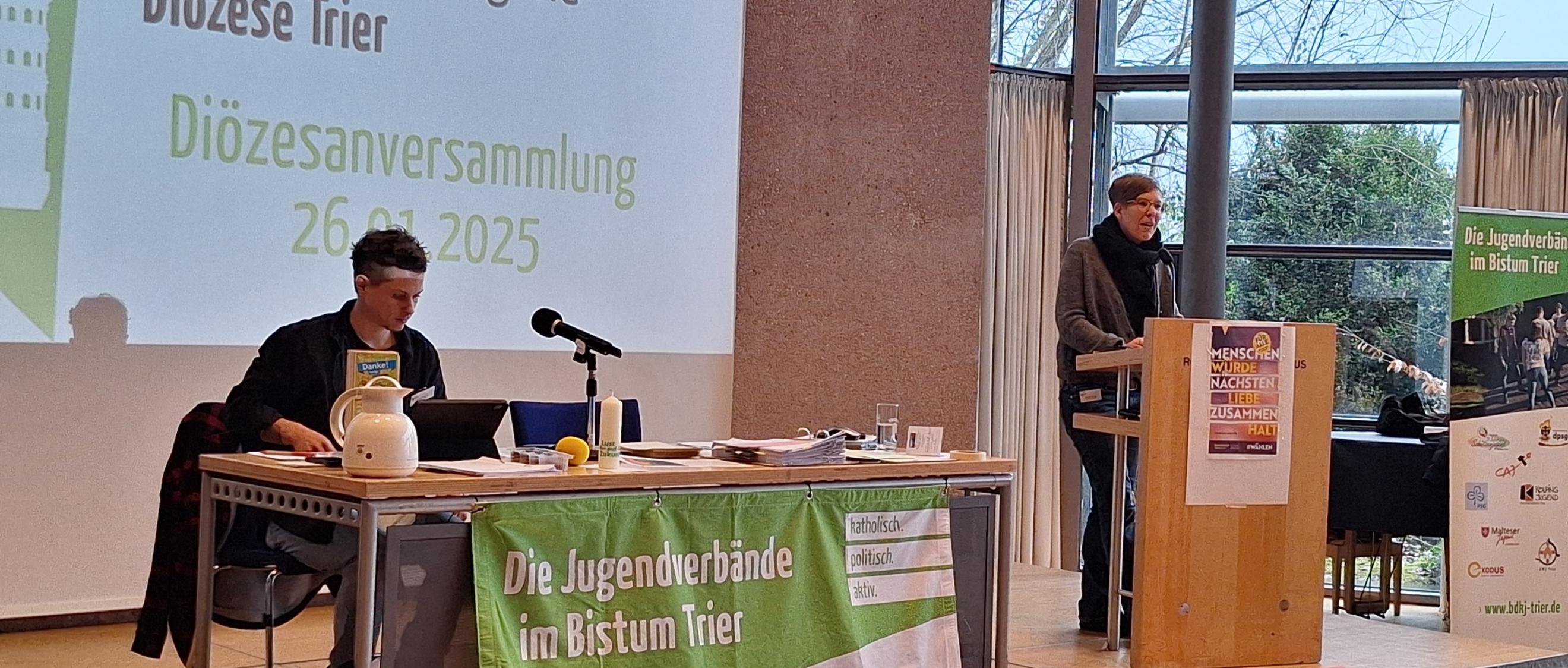 Das Bild zeigt ein Podest mit Rednerpult und Leinwand.