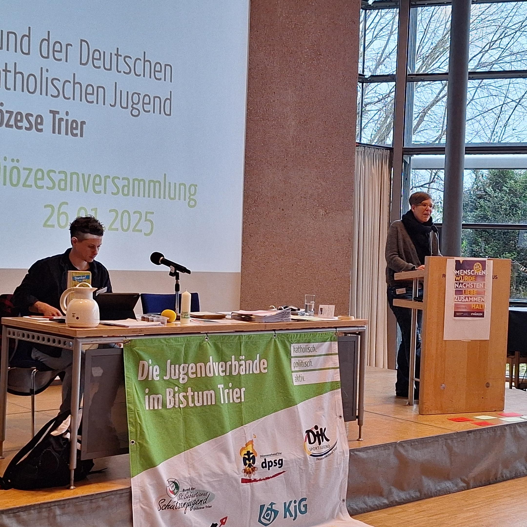 Das Bild zeigt ein Podest mit Rednerpult und Leinwand.